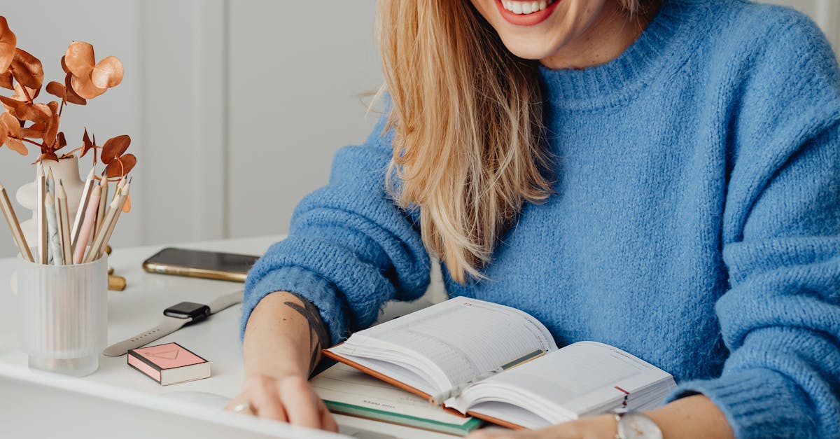 A cheerful woman in a blue sweater working remotely with a laptop in a cozy home setting.