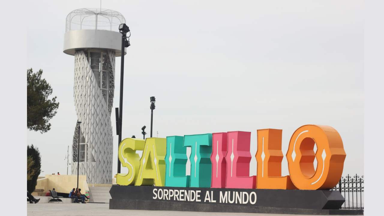A cheerful woman in a blue sweater working remotely with a laptop in a cozy home setting.
