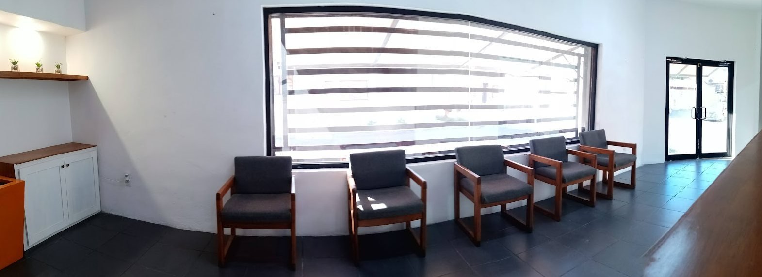 Sala de espera de Clínica Delta con cinco sillas junto a un ventanal